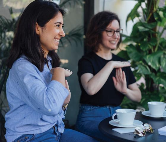 Two women using their hands to speak Auslan language