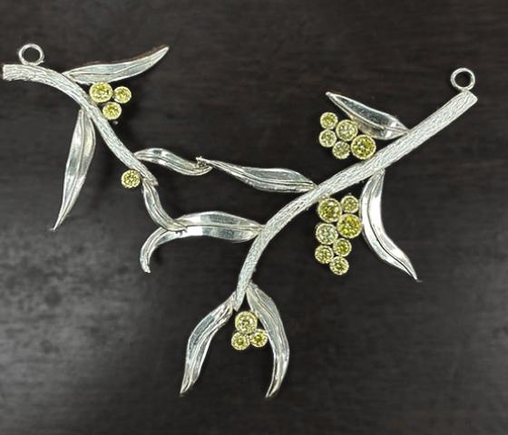Silver jewellery in the shape of baranches and leaves with green gemstones